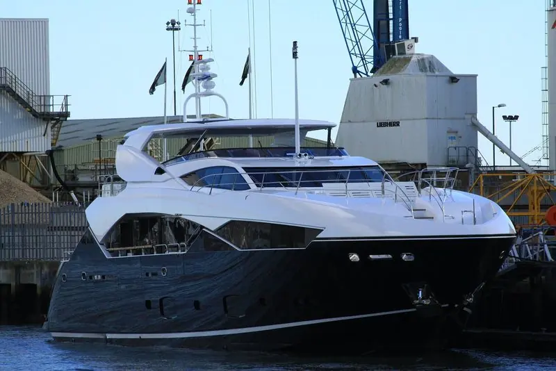 Dark hulled and freshly out, a Sunseeker lies under the harbour cranes at Poole.